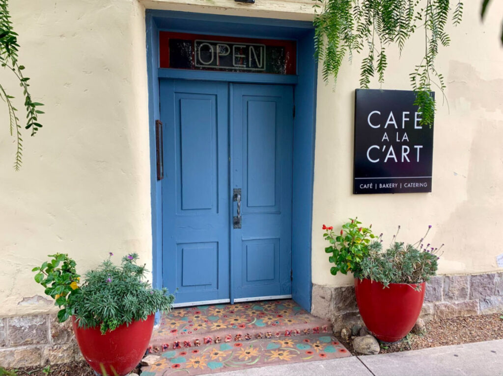 The facade of Café à la C'Art featuring its blue doors