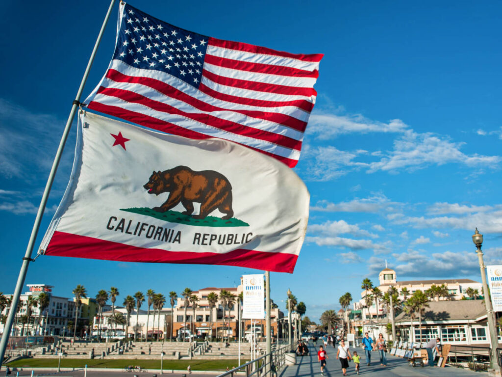 The California state and American flags with the cityscape in the background