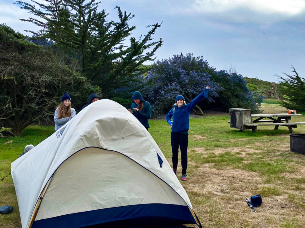 A group of friends setting up the tent at sunset campground