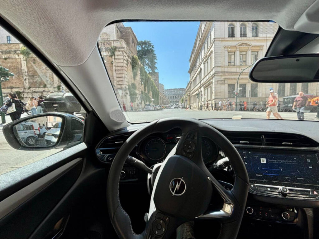View of the steering wheel of a car on the busy streets of Rome