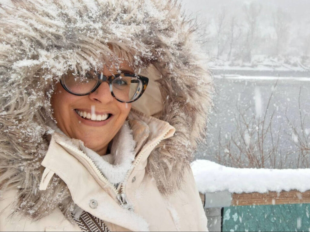 The author Catherine Driver, smiling for a photo along the Bow River on a snowy day