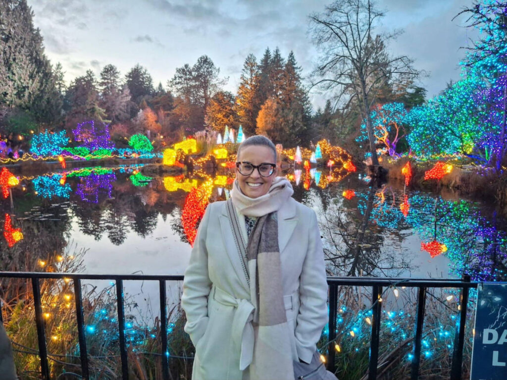 The author Catherine Driver, standing near the lake surrounded by Christmas decorations in VanDusen Botanical Garden