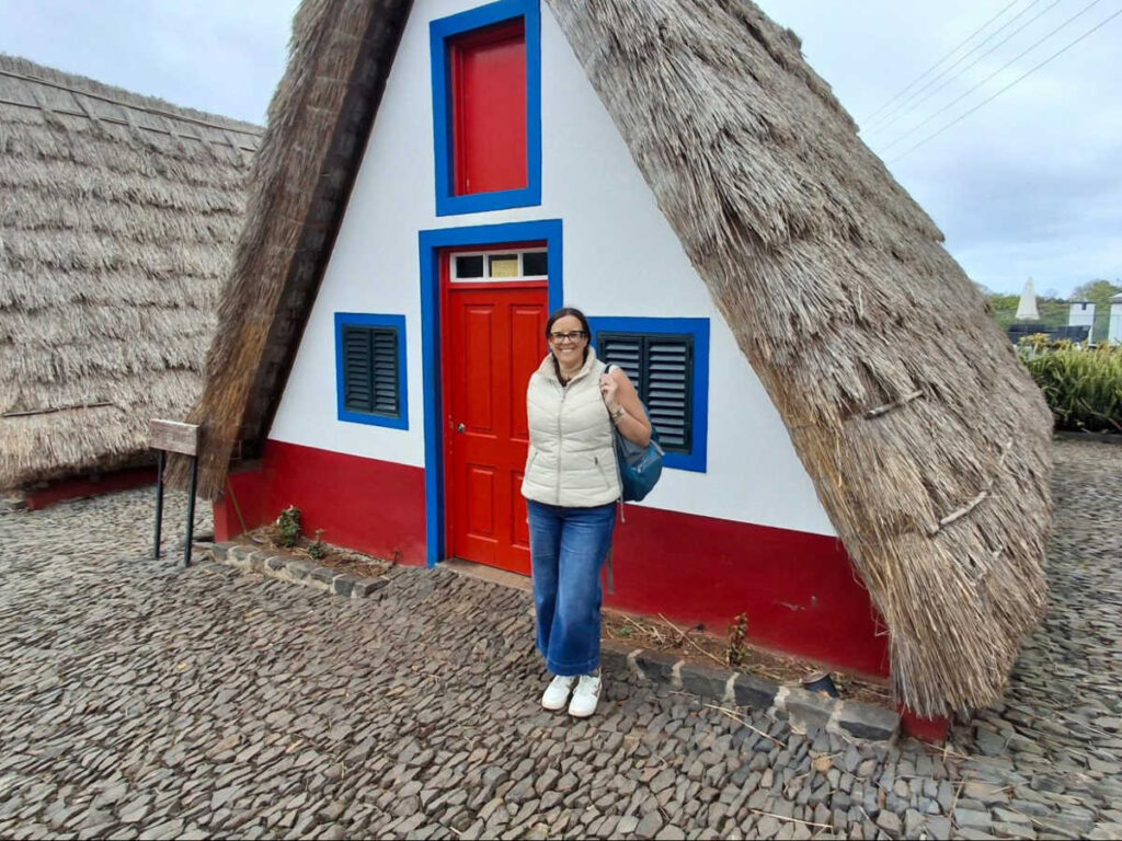 The author Catherine Driver, posing for a photo in front of the traditional casas de colmo 