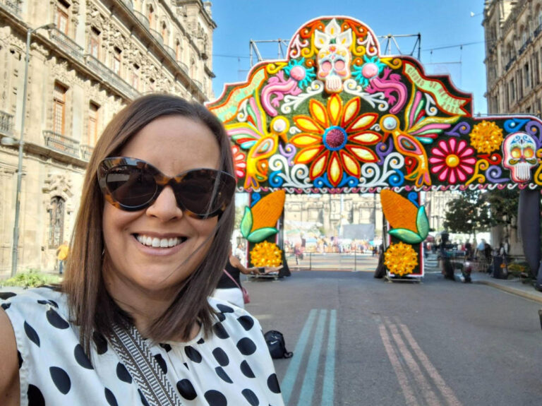 Travel Lemming writer Catherine Driver, smiling for a photo in front of the colorful entrance gate to the Zócalo