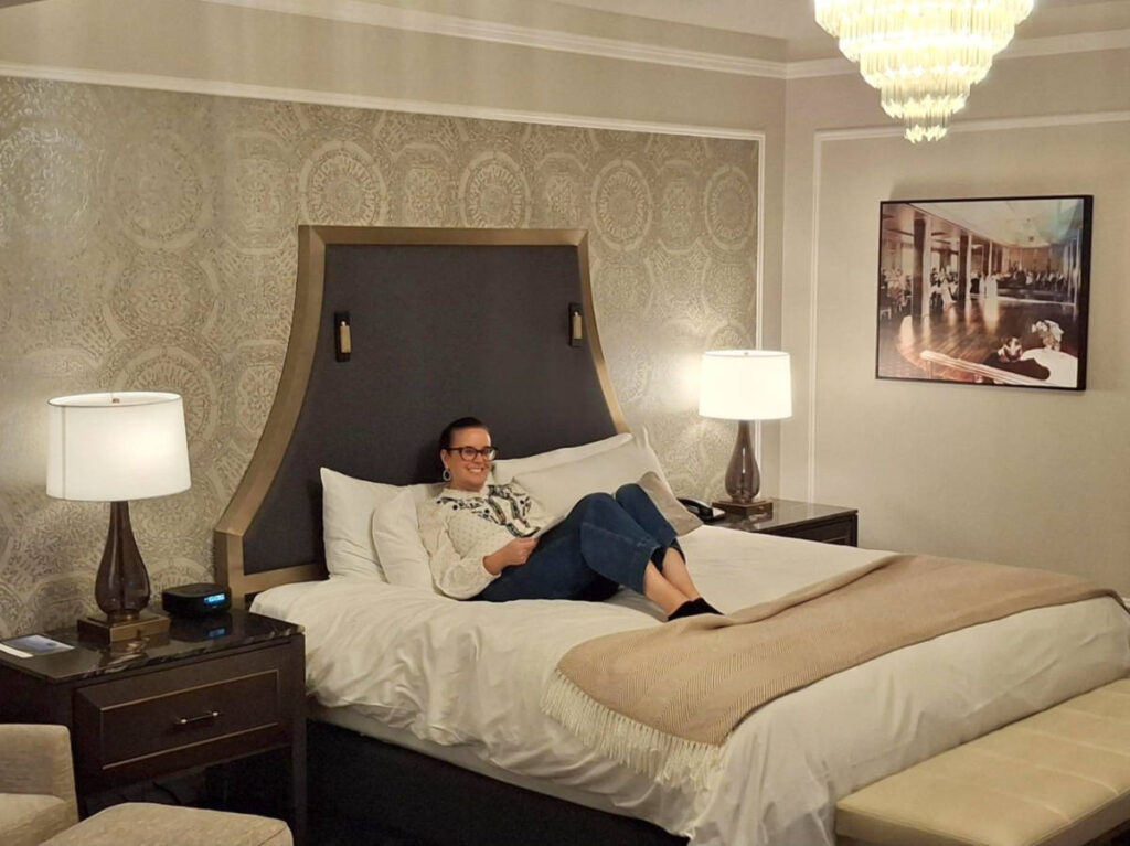 The author Catherine Driver, sitting on the bed at the Fairmont Hotel Vancouver 