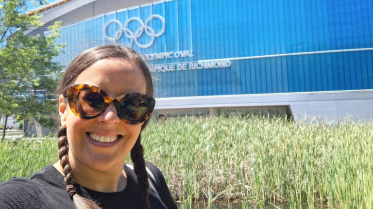 The author Catherine Driver, smiling for a photo with the Olympic Oval in the background