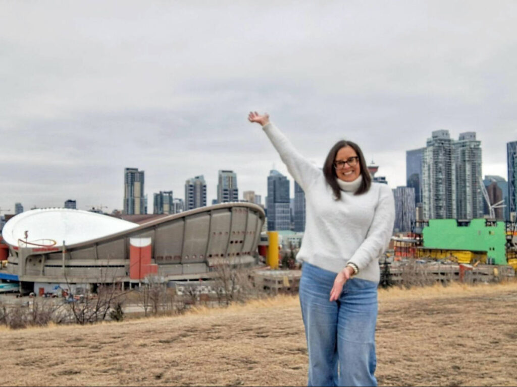 The author Catherine Driver, posing for a photo with an overlooking view of Calgary from Scotsman’s Hill