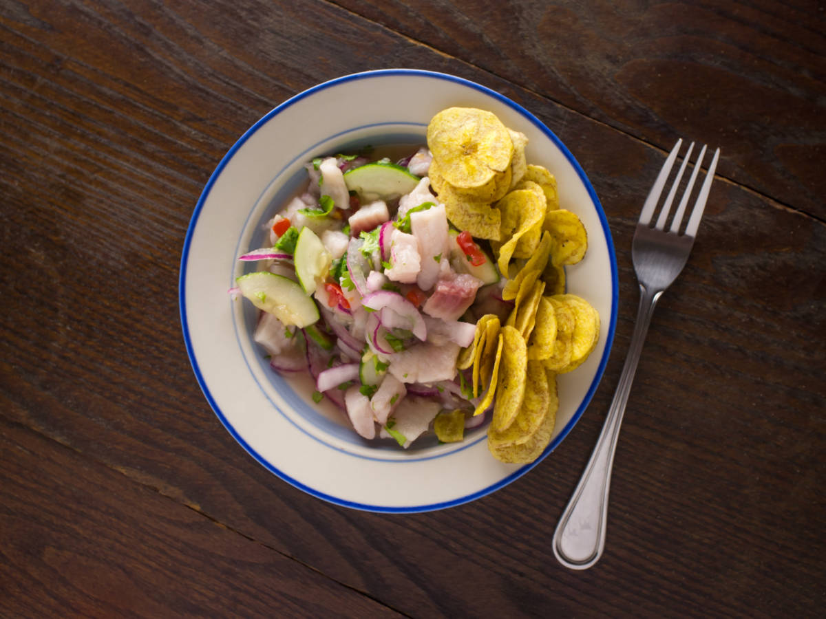 A plate of Chilled spicy ceviche with crispy fried plantain chips next to a fork