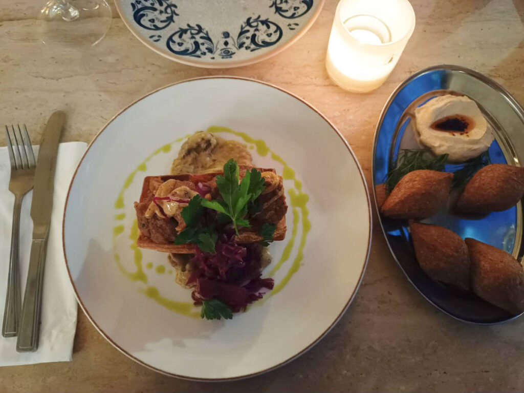 A candle lit table with a plate of Chef's Beyti and Kibbeh at Longa