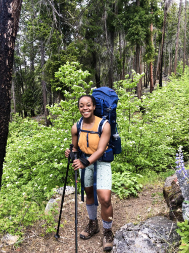 The author Chelsea Booker posing for a photo on the trail surrounded by dogwoods