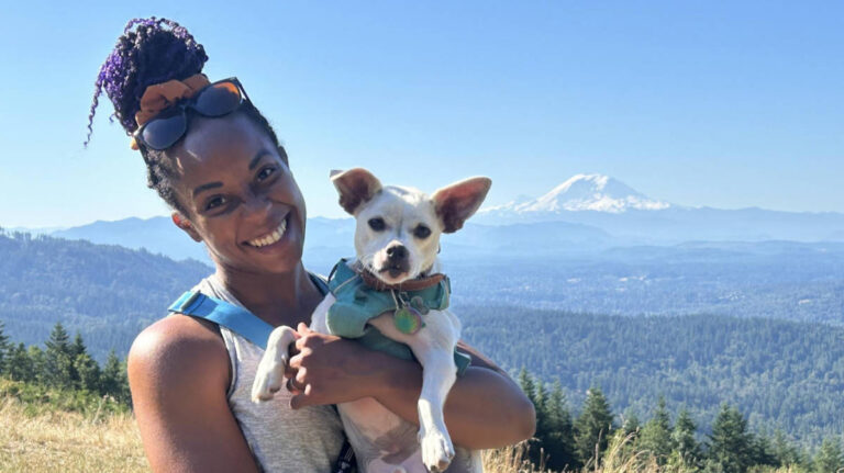 The author Chelsea Booker carrying her dog, Toby, with a view of the Mount Rainier