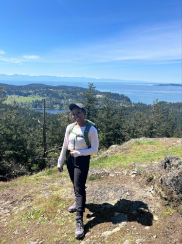 The author Chelsea Booker smiling for a photo with scenic overlooking view from Sugarloaf Mountain