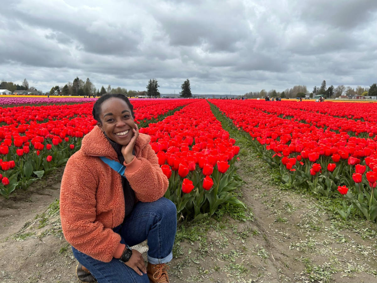 The author Chelsea Booker, posing for a photo in front of the vibrant tulips field