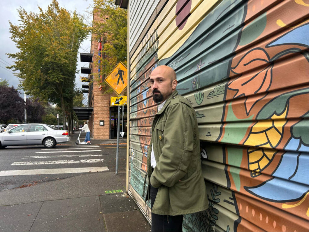 The author's husband, standing in front of the mural at a  vintage shop on Belmont