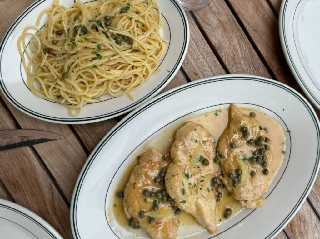 A plate with chicken picatta and spaghetti on the side