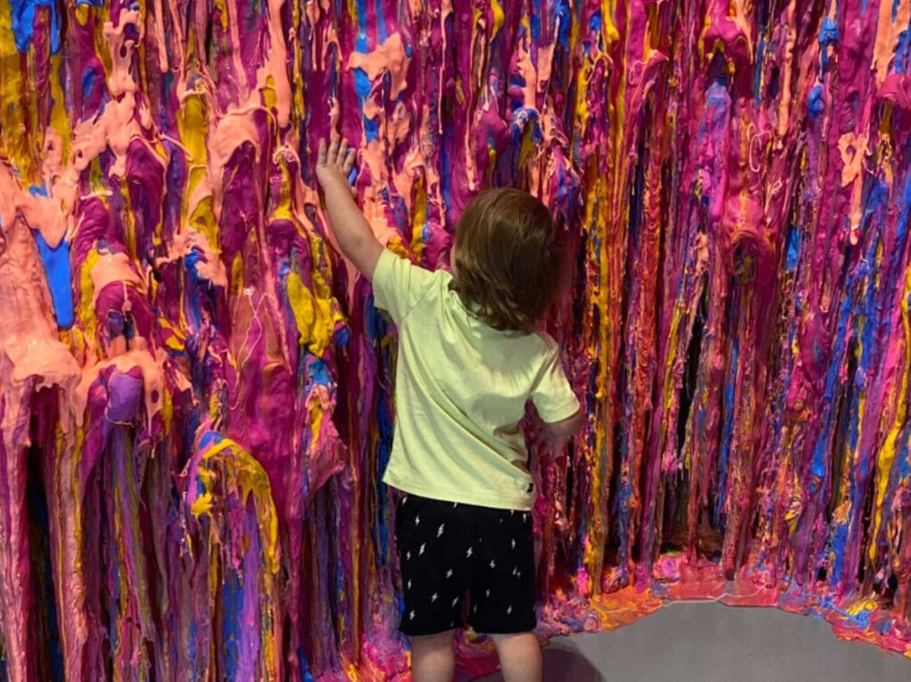 A child enjoying the colorful slime on the wall