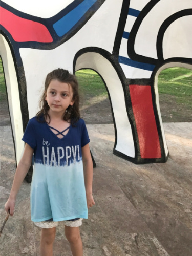 A child standing in front of the Monument au Fantone sculpture by Jean Dubuffet