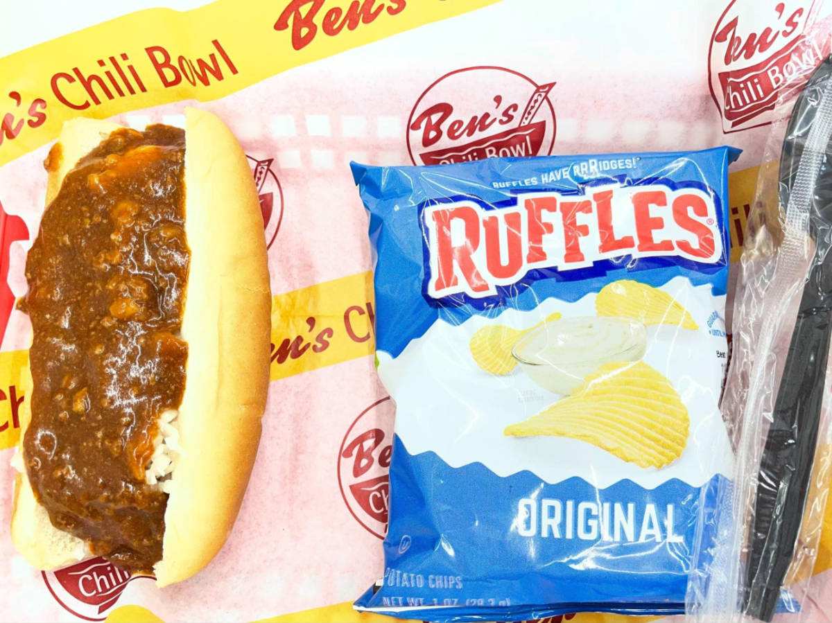 A chili dog on a bun and a pack of chips