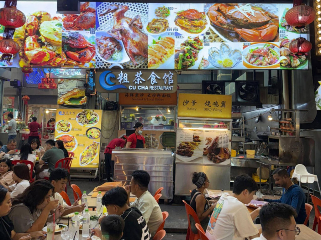 A group of people eating at a Chinese-style seafood at Jalan Alor food street