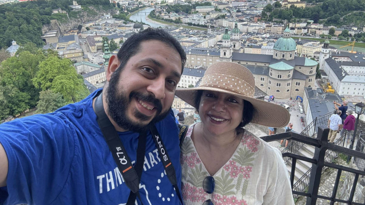 The author Christina Daniels and her husband, smiling for a photo with an overlooking view of the Salzburg
