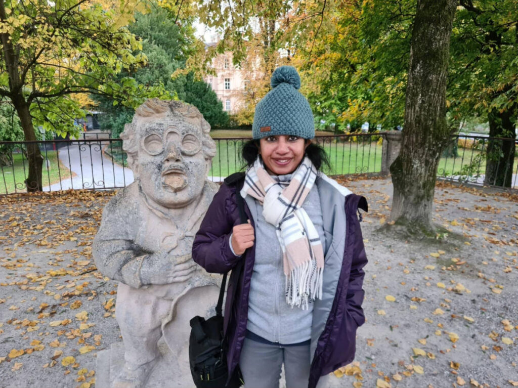 The author Christina Daniels, standing next to the dwarf statue at the Mirabell Gardens