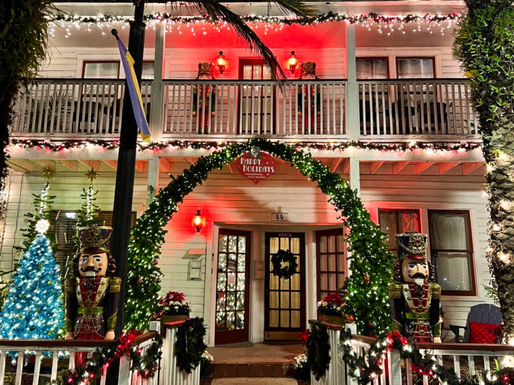 Exterior view of a festive house with Christmas tree and decorations on front steps illuminated at night