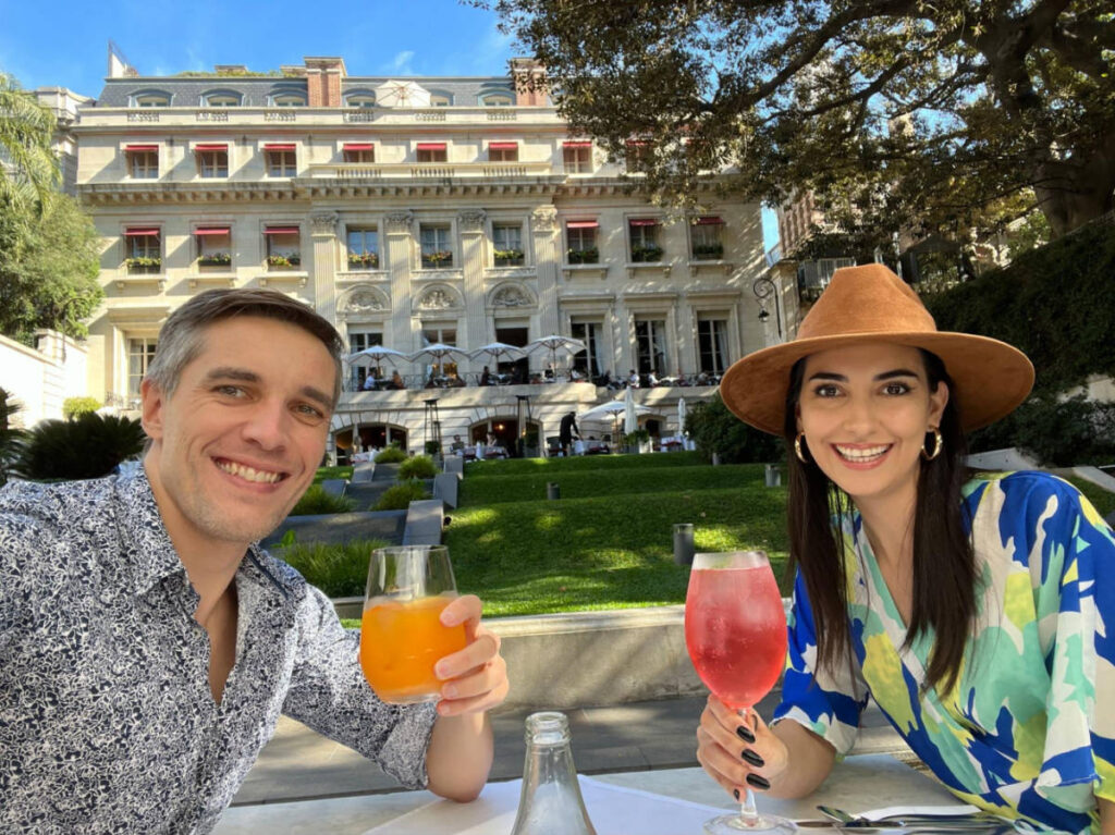 Travel Lemming founder, Nate Hake and Clara Kesseler, enjoying their drink at an open area surrounded by greenery outside Palacio Duahu