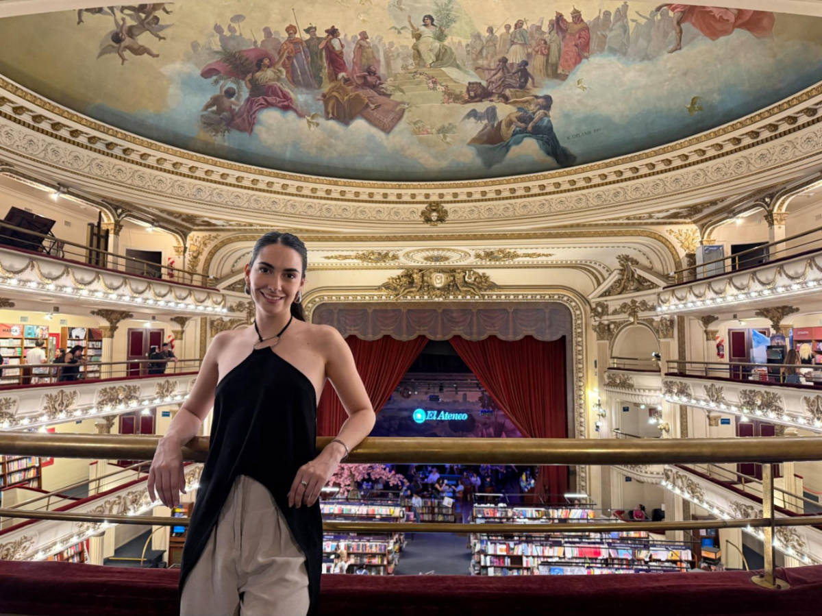 Travel Lemming writer Clara Kesseler, posing for a photo with an overlooking view of the book shelves and painted ceiling in El Ateneo Gran Splendid
