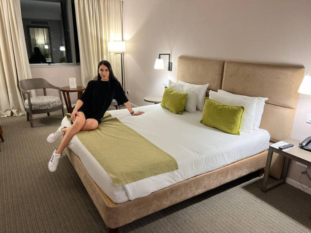 Travel Lemming writer Clara Kesseler, sitting on the huge bed in Howard Johnson Plaza Buenos Aires