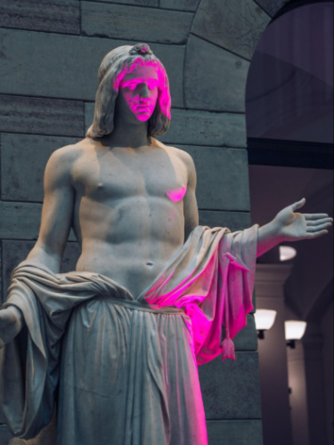 A neon light reflecting on the classic statue