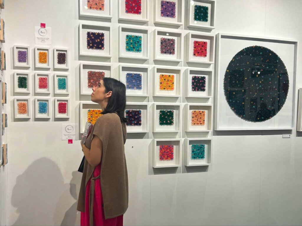 The author Claudicet Pena, admiring the colorful framed art in a gallery
