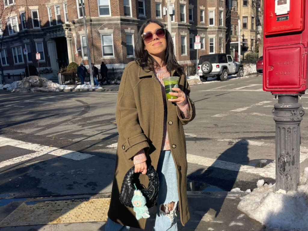 The author Claudicet Pena, enjoying her matcha latte in the streets of Boston on a sunny day