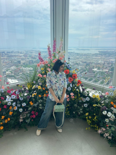 The author Claudicet Pena, admiring the flowers with an overlooking view of Boston