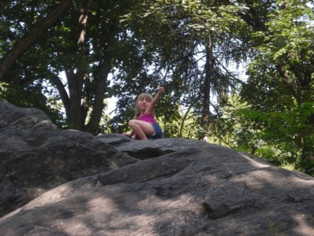 A little girl at the top during their climbing rocks activity in Central Park