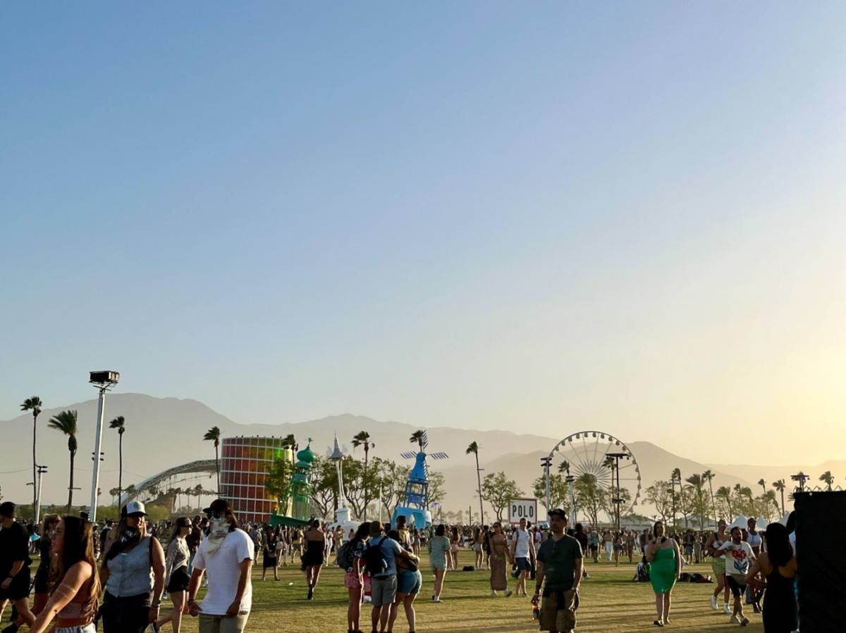 The crowd, art installations and ferris wheel at the Coachella Festival grounds at sunset