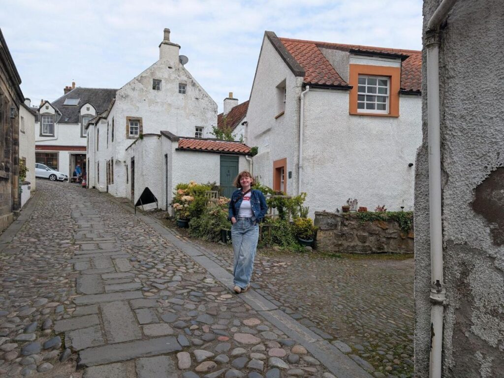 Author Louise standing on the cobblestoned streets of Culross