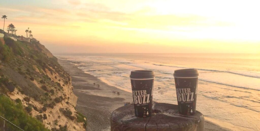Two coffee cups on a cliff overlooking the ocean at sunset