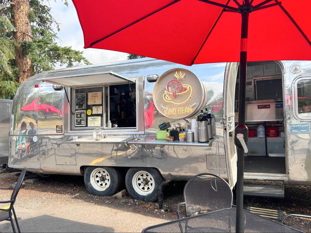 View of the tables and chairs in front of a coffee truck 