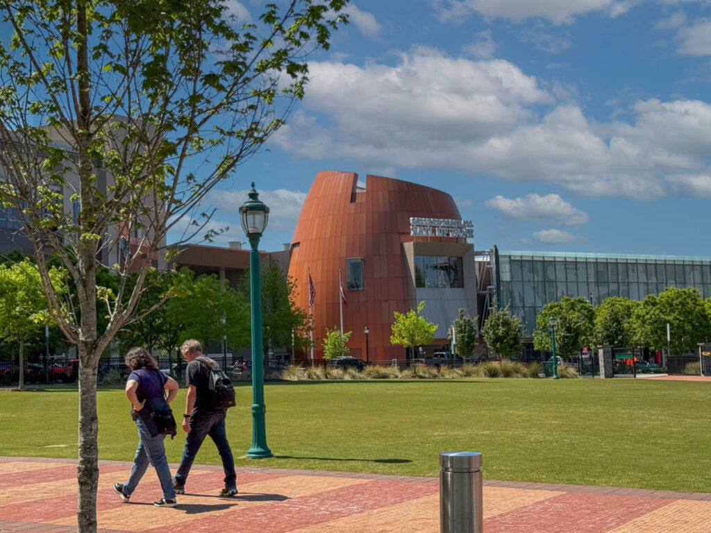 A couple walking along the pathway with the College Football Hall of Fame seen from across the lawn