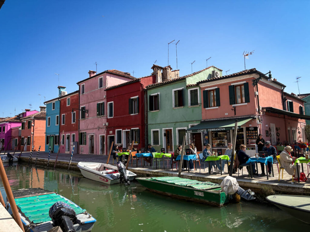 View of the boats on the canals in front of the color-filled street scene in Burano