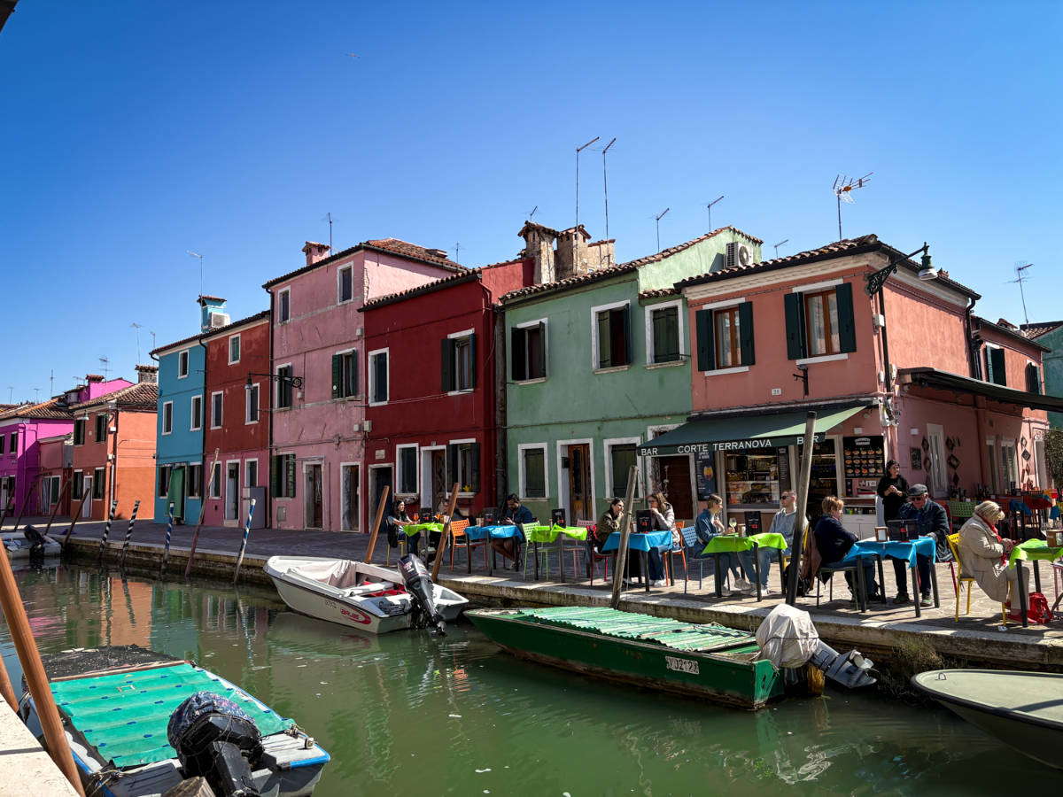 View of the boats on the canals in front of the color-filled street scene in Burano