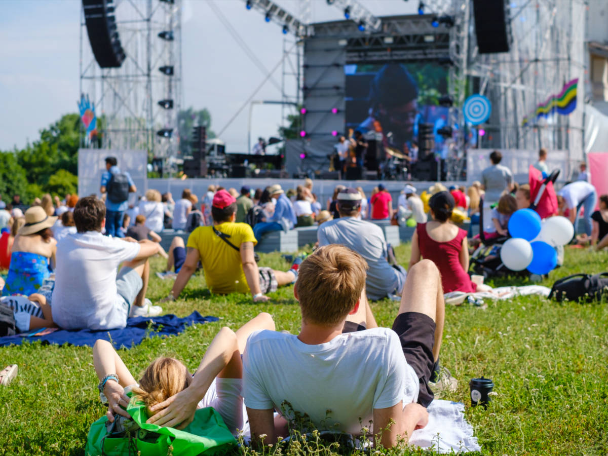 A group of people sitting on a field while watching a performance in TGIF Concerts In the Park