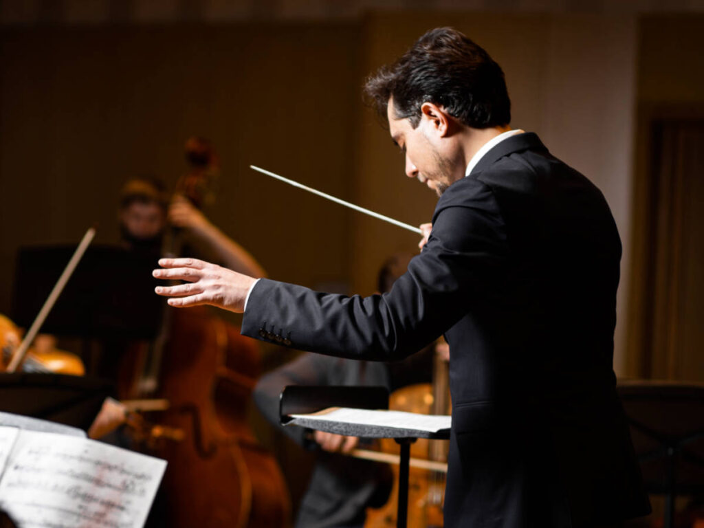 Closeup view of the conductor of an orchestra inside the concert hall