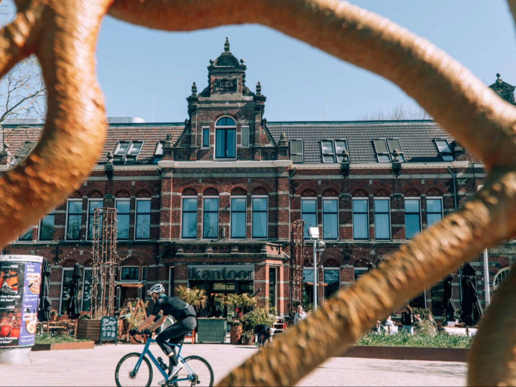 A man cycling in front of the Conscious Hotel