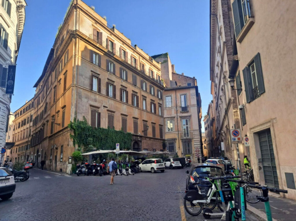 A street in Rome featuring parked cars and bicycles alongside historic buildings