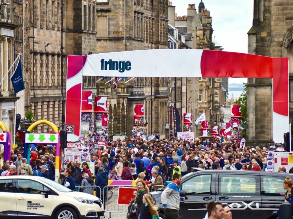 View of the bustling street with an arch sign of Edinburgh Festival Fringe