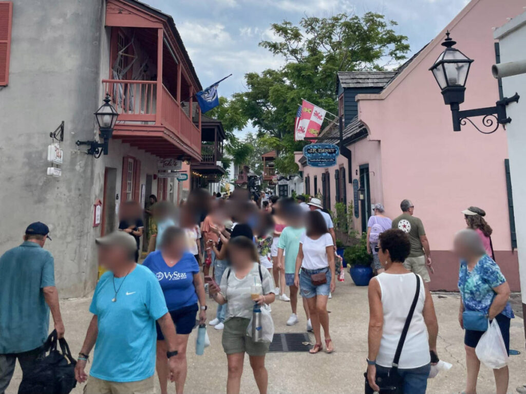 People walking along a bustling street with flags around in the Historic District