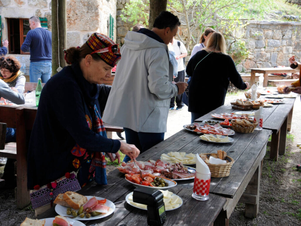 People getting food on the table featuring the Culinary flavors of Croatia