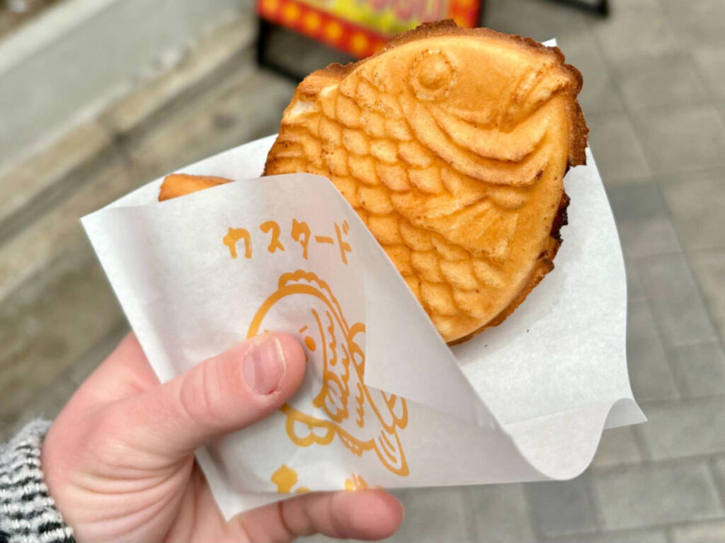 A hand holding a custard-filled taiyaki