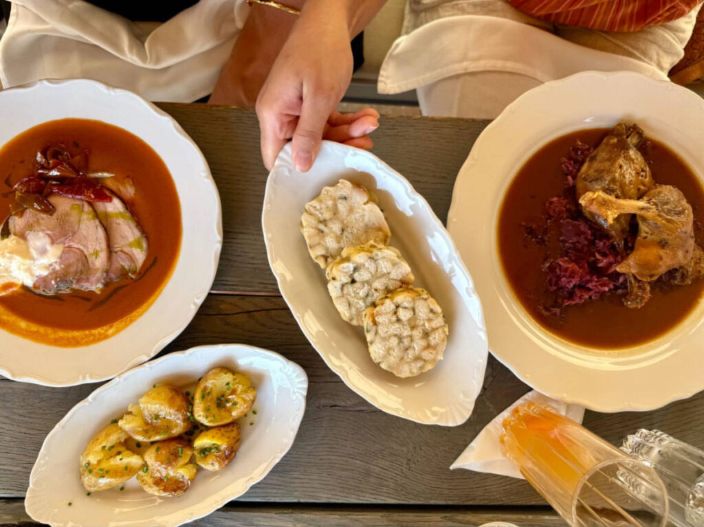 Closeup look of the braised pork shoulder, roasted duck leg, baked potatoes, and bread dumplings at Kuchyn